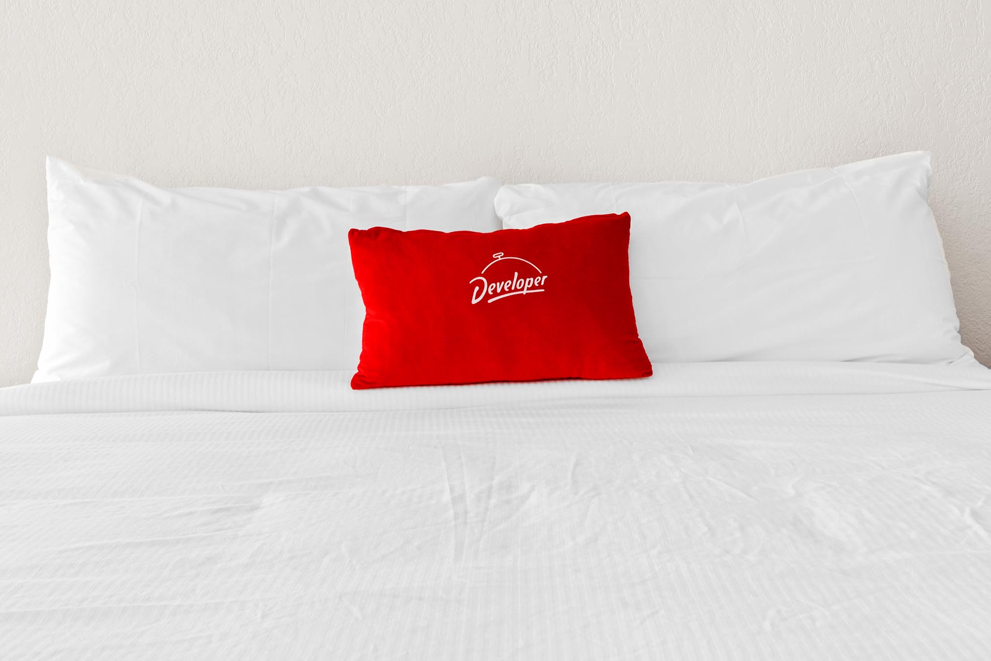 Queen bed with white sheets and red pillow