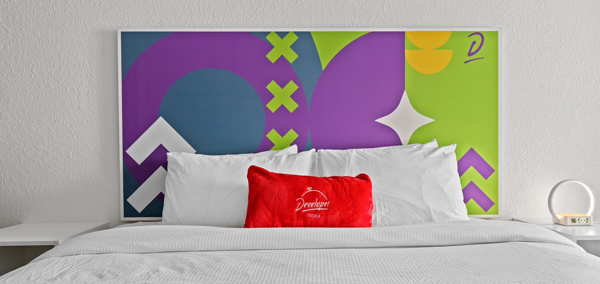 Rendering of king bed with white sheets, colorful wall art