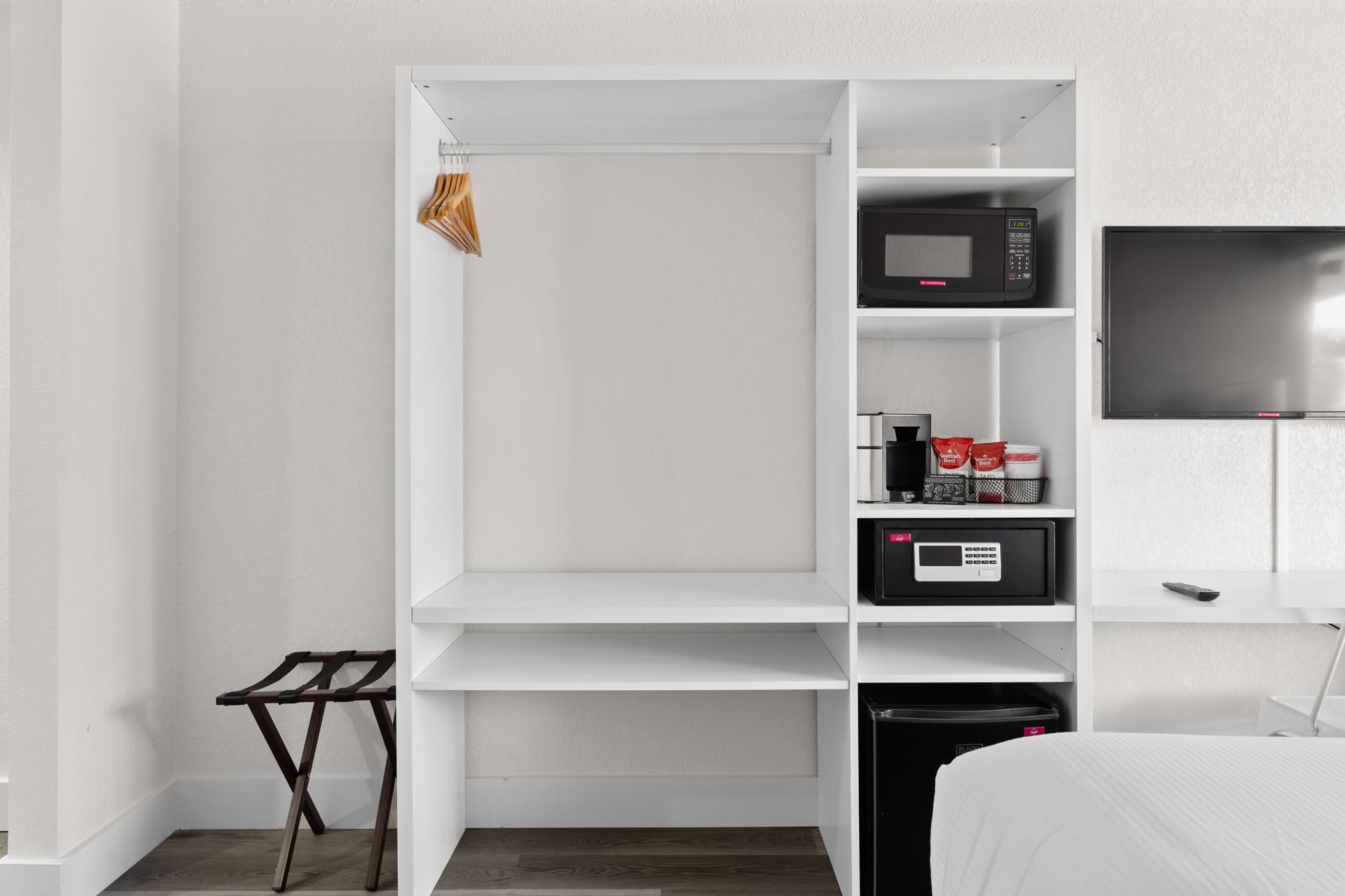 Wall unit closet with mini fridge, microwave, safe, and mounted TV